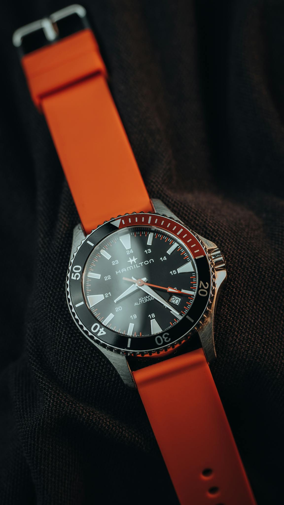 Close-up of a luxury wristwatch with orange strap and black dial, highlighting its elegance and style.