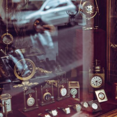 Vintage clock collection showcased in a Roman shop with reflective glass and elegant designs.